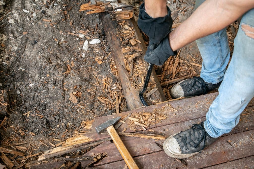 Man removing hardwood floors with heavy tools. 