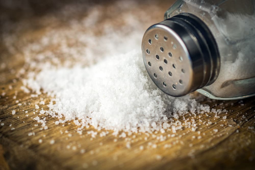 how to get blood out of carpet; closeup of a salt shaker next to spilled salt on a table