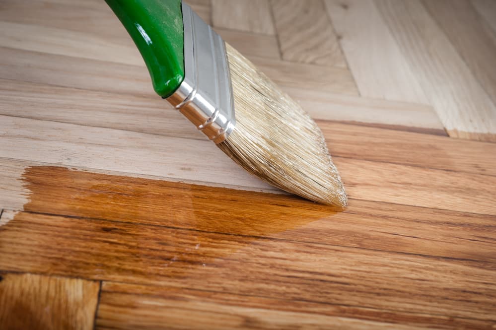 Varnish brush applying varnish to wooden planks